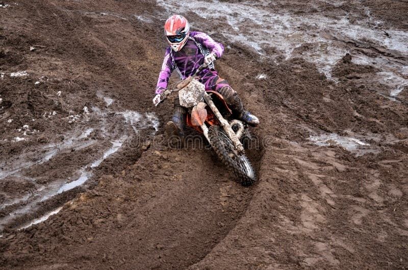 Motorcrosser rijdt met een crossmotor door een diepe modderige bocht