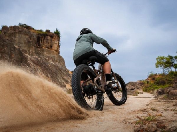 Mountainbiker rijdt door los zand op een rotsachtig parcours