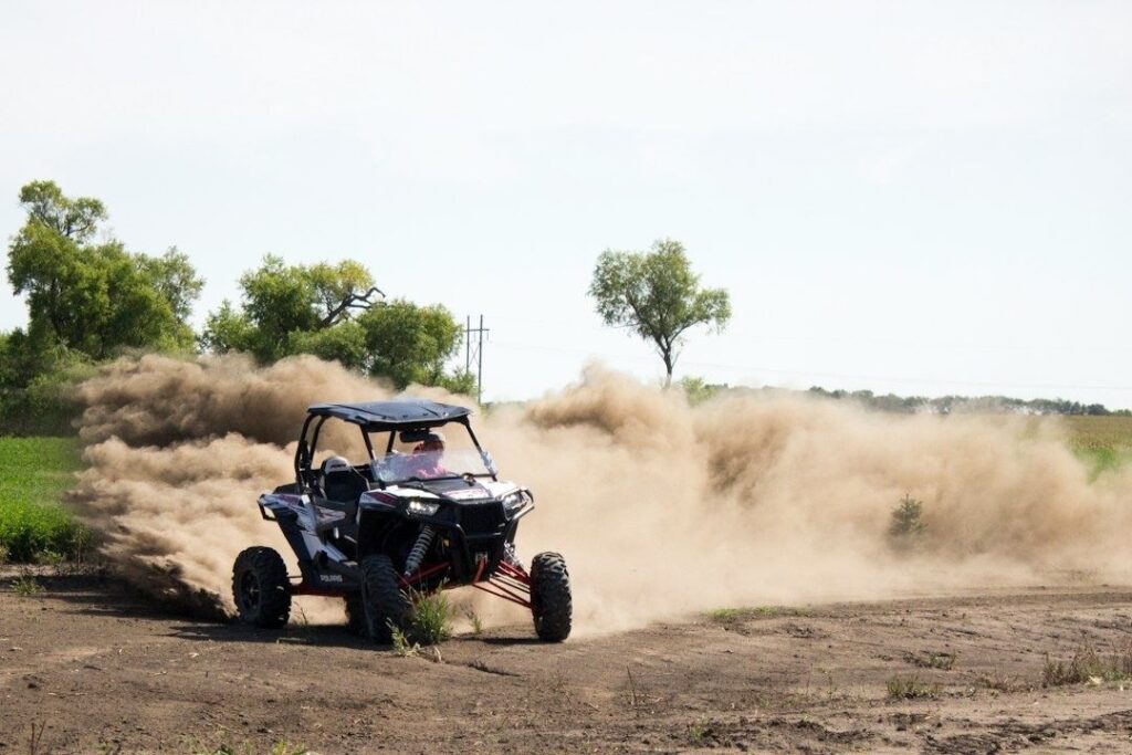 Offroadbuggy raast over een veld en veroorzaakt een grote stofwolk